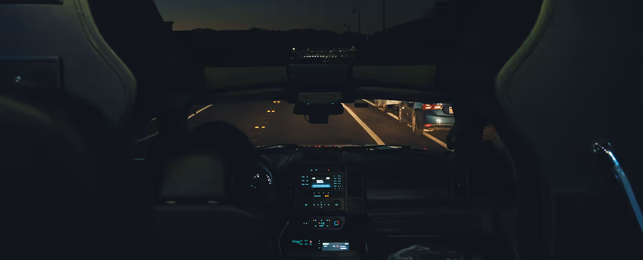 View from the driver's seat of a chauffeured vehicle on a Las Vegas road at night.