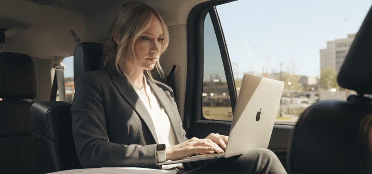 Business executive working on laptop in chauffeured luxury vehicle