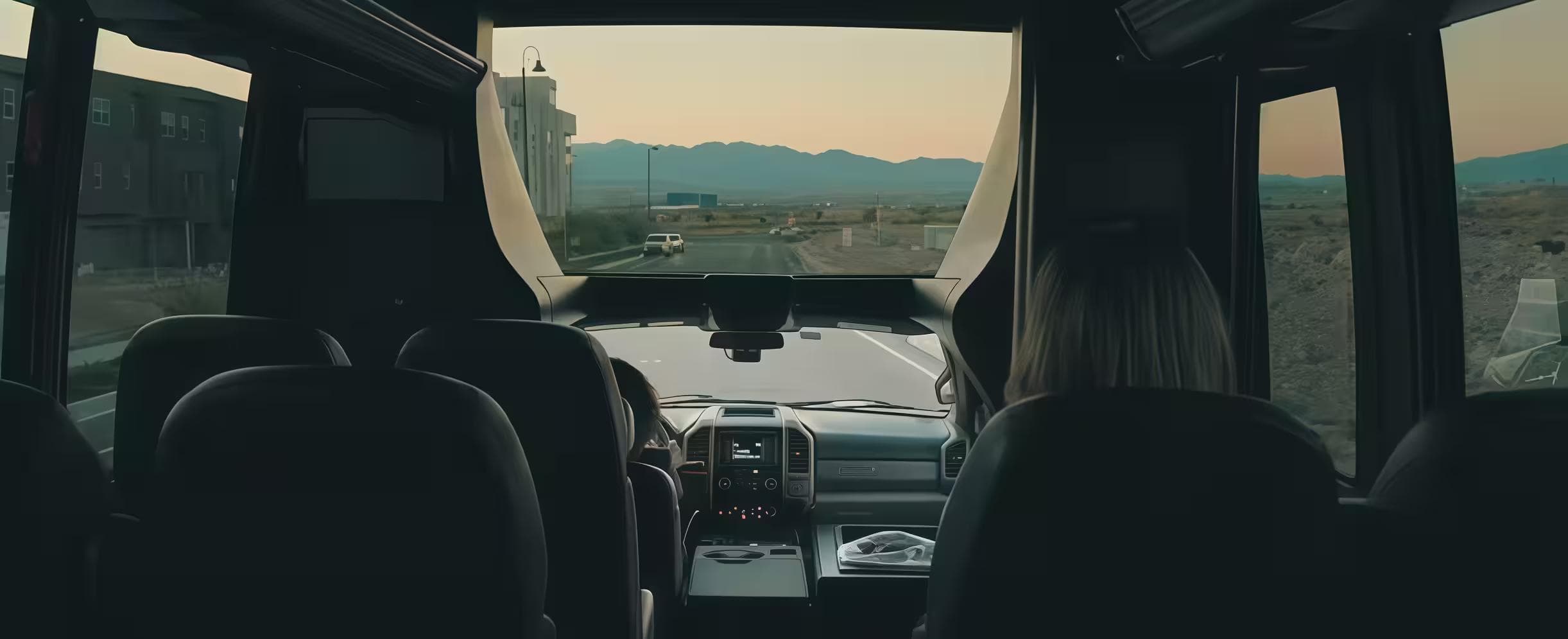 Interior view of a passenger van or shuttle bus driving toward mountains