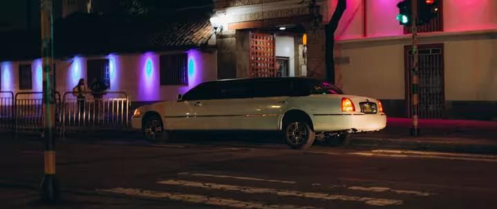 Classic white stretch limousine parked on city street at night