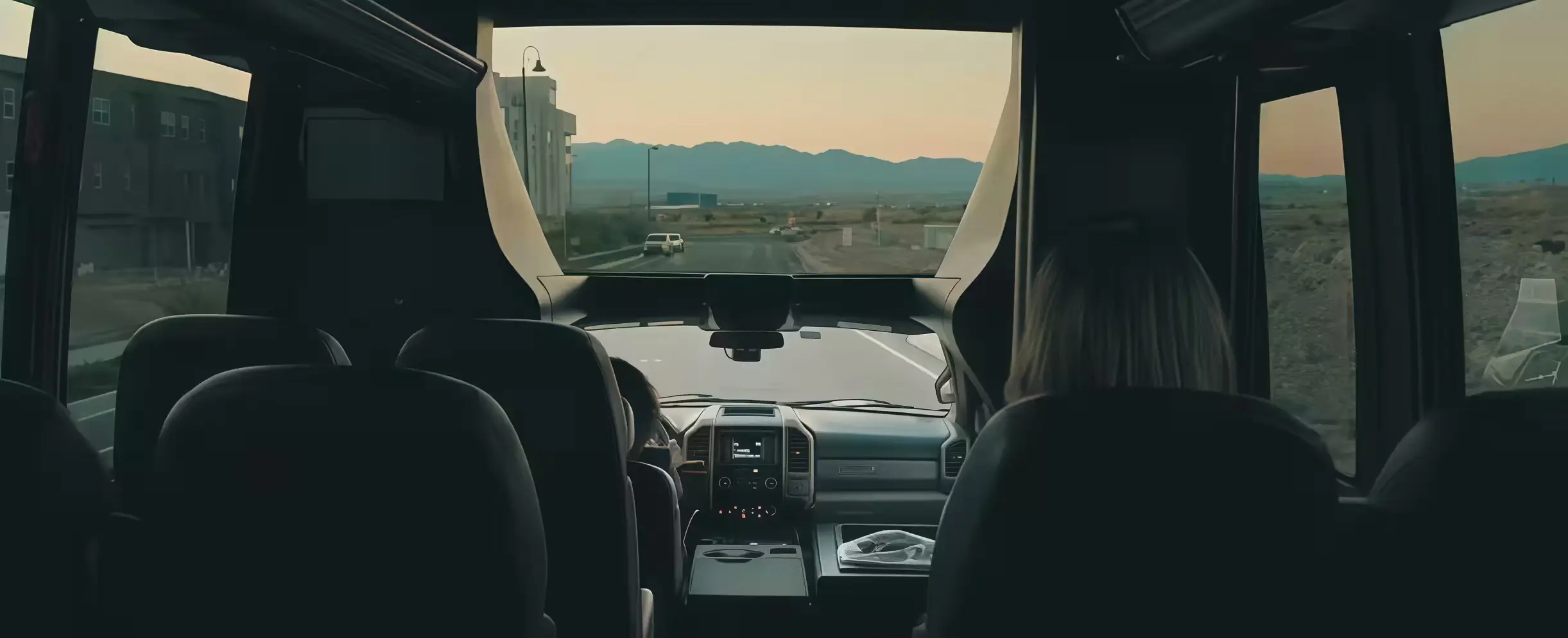 Interior view of a passenger van or shuttle bus driving toward mountains