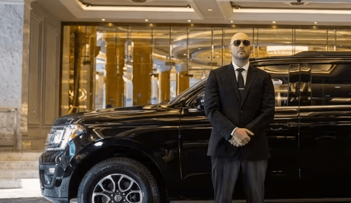 Professional Omni Limousine chauffeur in suit standing by luxury vehicle