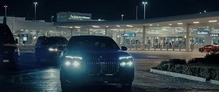 Luxury executive sedan picking up passengers at airport terminal at night